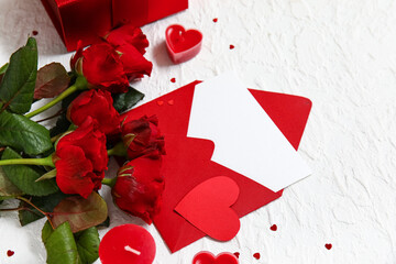 Envelope with blank greeting card, hearts and bouquet of roses on white grunge background....