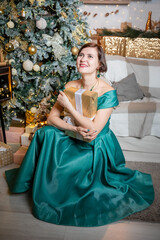 Woman in Elegant Dress Holding Gift by Christmas Tree