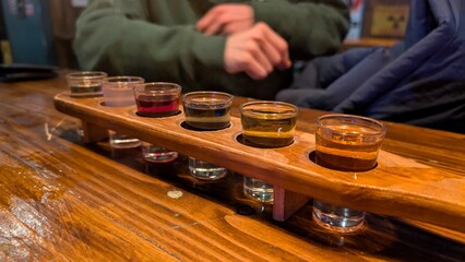 Flight of alcoholic shots on a wooden paddle in a bar with friends socializing