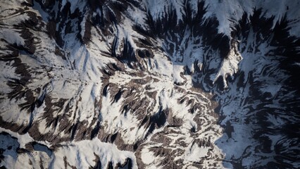 A breathtaking panorama showcases rugged mountain peaks blanketed in pristine snow. The winter landscape reveals intricate patterns and shadows under a clear, crisp sky, evoking tranquility.