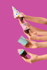 Many female hands with birthday cupcakes, disposable cups and party hat on purple background