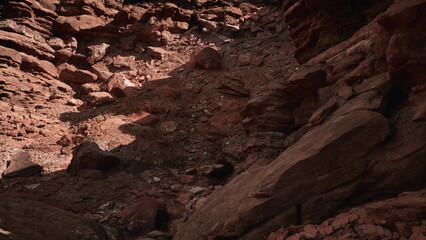 Beneath the vibrant hues of dusk, a rugged canyon unfolds with striking red rock formations and scattered boulders.