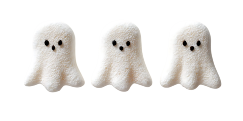 Three adorable fluffy white ghost-shaped candies with black eyes and mouths, isolated on a white background.
