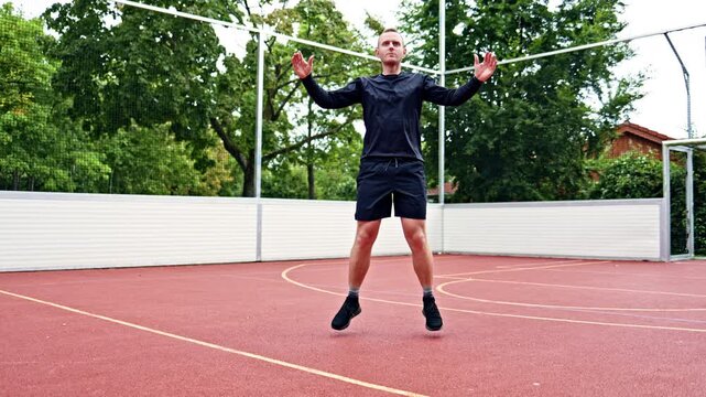 Young athletic man doing sports on a sports ground on the street. A man maintains a healthy lifestyle and does sports in a city park. A man in shorts and a black jersey.
