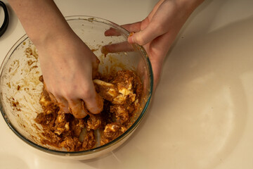 Top view of hands kneading sticky cookie dough in a glass bowl. Preparing ingredients for homemade Christmas baking
