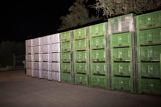 Stacked Green and White Plastic Agricultural Crates at Night