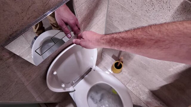 Man pressing toilet button to flush water.