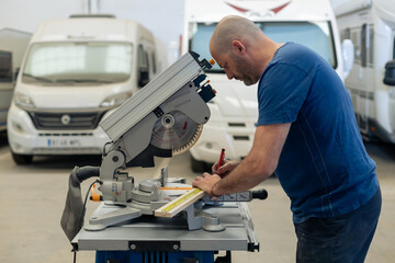 A young craftsman restores a caravan in a hangar.