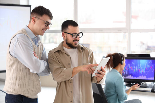 Male traders working with tablet computer in office