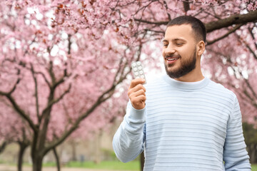 Young man holding pills from allergy outdoors