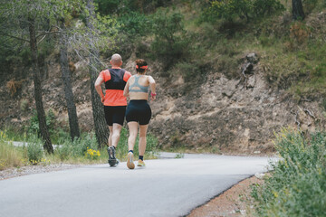 Fit couple running on forest road for outdoor exercise and fitness motivation