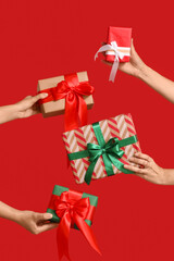Many female hands with Christmas gift boxes on red background