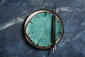 Chinese table setting with plates and chopsticks on grunge blue background
