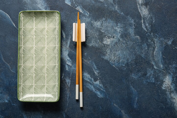 Chinese table setting with plate and chopsticks on grunge blue background