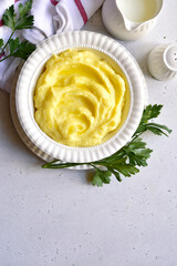 Mashed potato with cheese and herb in a white bowl. Top view with copy space.