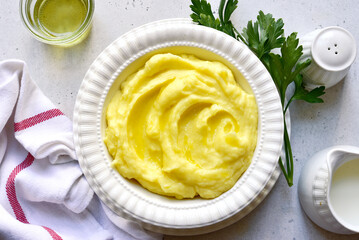 Mashed potato with cheese and herb in a white bowl. Top view with copy space.