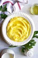 Mashed potato with cheese and herb in a white bowl. Top view with copy space.