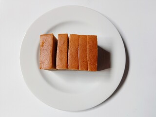 slice of lapis legit cake on plate. close-up of indonesian layer cake lapis legit slices on white plate.