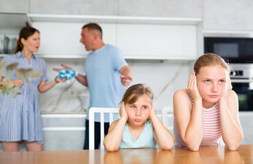 Kids feels upset while parents quarrel at background. Sad little girl and boy frustrated with...