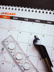 Close-up of January desk calendar with ruler, pen, and holiday dates for New Year planning.

