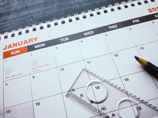 Close-up of January desk calendar with ruler, pen, and holiday dates for New Year planning. Education, study, and business schedule concept featuring a ruler and pen on a calendar page.