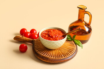 Bowl of tasty tomato sauce and ingredients on beige background, closeup