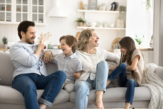 Overjoyed mom dad play tickle game with diverse little kids