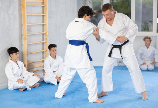 Proficient judo master teaching his underage students martial art during workout session