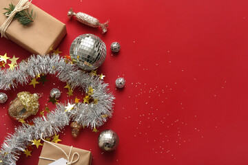 Composition with disco balls, gift boxes and Christmas decor on red background