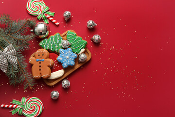 Composition with disco balls, fir tree branches and Christmas cookies on red background