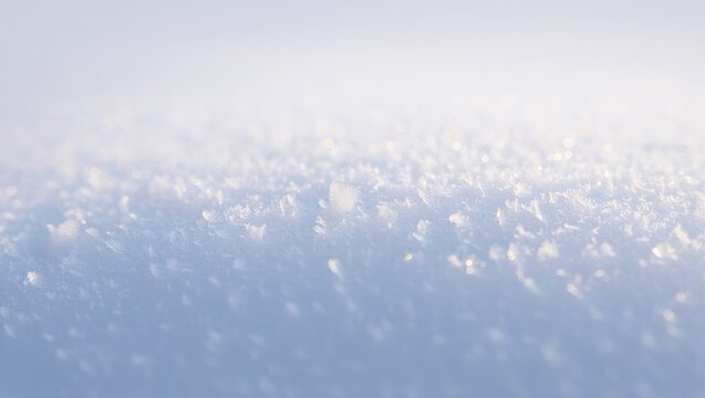 Fresh white snow sparkling with tiny ice crystals and frost under bright winter sunlight, creating a cold abstract background texture with soft blue and white hues
