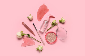 Composition with white rose flowers, bottle of cosmetic product and facial massage tools on pink...