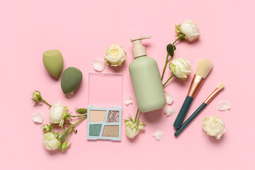 Composition with white rose flowers, bottle of cosmetic product and makeup brushes on pink background