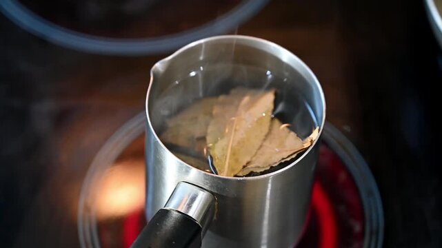 Aromatic bay leaf decoction brewing in a pot on an electric stove.
