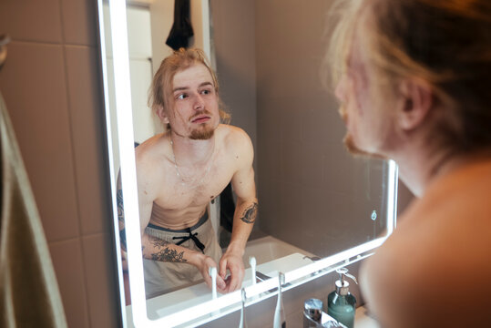 Man prepares for stage by practicing expressions and grooming