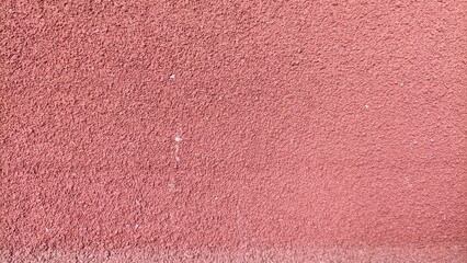 texture of red sandpaper surface showing coarse abrasive grains