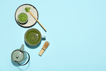 Naklejka premium Cup of fresh matcha tea with powder, chasen, chashaku and teapot on blue background