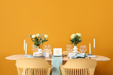 Table setting for Nobel prize day with burning candles and roses on orange background