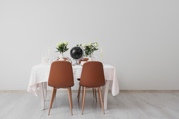 Table setting for Nobel prize day with globe and roses near light wall
