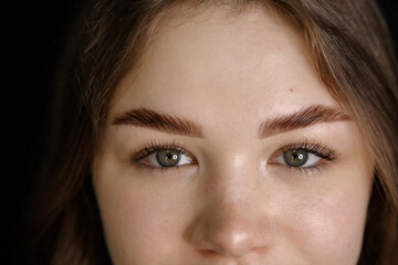 Obraz premium Close-up portrait of a young woman showcasing expertly shaped eyebrows and long eyelashes