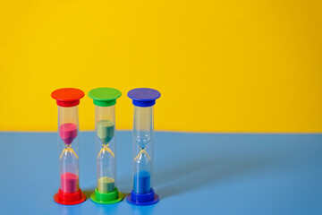 Hourglasses on blue and yellow background with copy space
