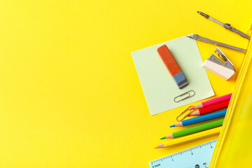 Eraser with different stationery on yellow background