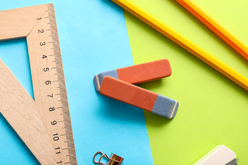 Erasers with stationery on color background