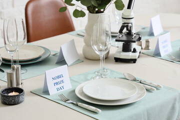 Elegant table setting for Nobel prize day with microscope and candles in dining room