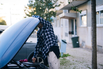 Young man in flannel reviews engine and battery prior to busy delivery day