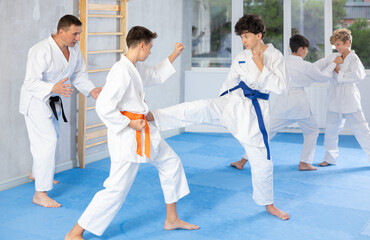 Diligent preteen karate students practicing fighting techniques during workout session