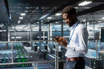 African american IT scientist manage storage for deep learning training workflow, analytics tools. Server hub engineer on industrial platform performing maintenance on AI processing tasks.