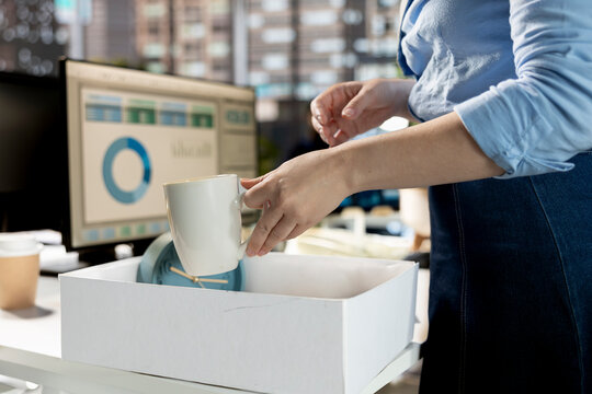 Hopeful female newbie installing her office supplies at her new workstation, feeling optimistic about the new beginning. Woman unpacking and settling in at her new corporate job. Close up.