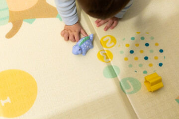 Baby playing with dinosaur toy on learning playmat