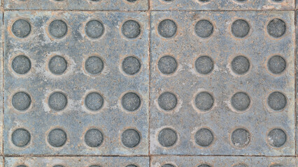 Close-up of gray tactile paving slabs with raised dot pattern for visually impaired assistance. Hydraulic cement tiles, square pedestrian tile floor texture. Accessibility, urban environment, outdoor 